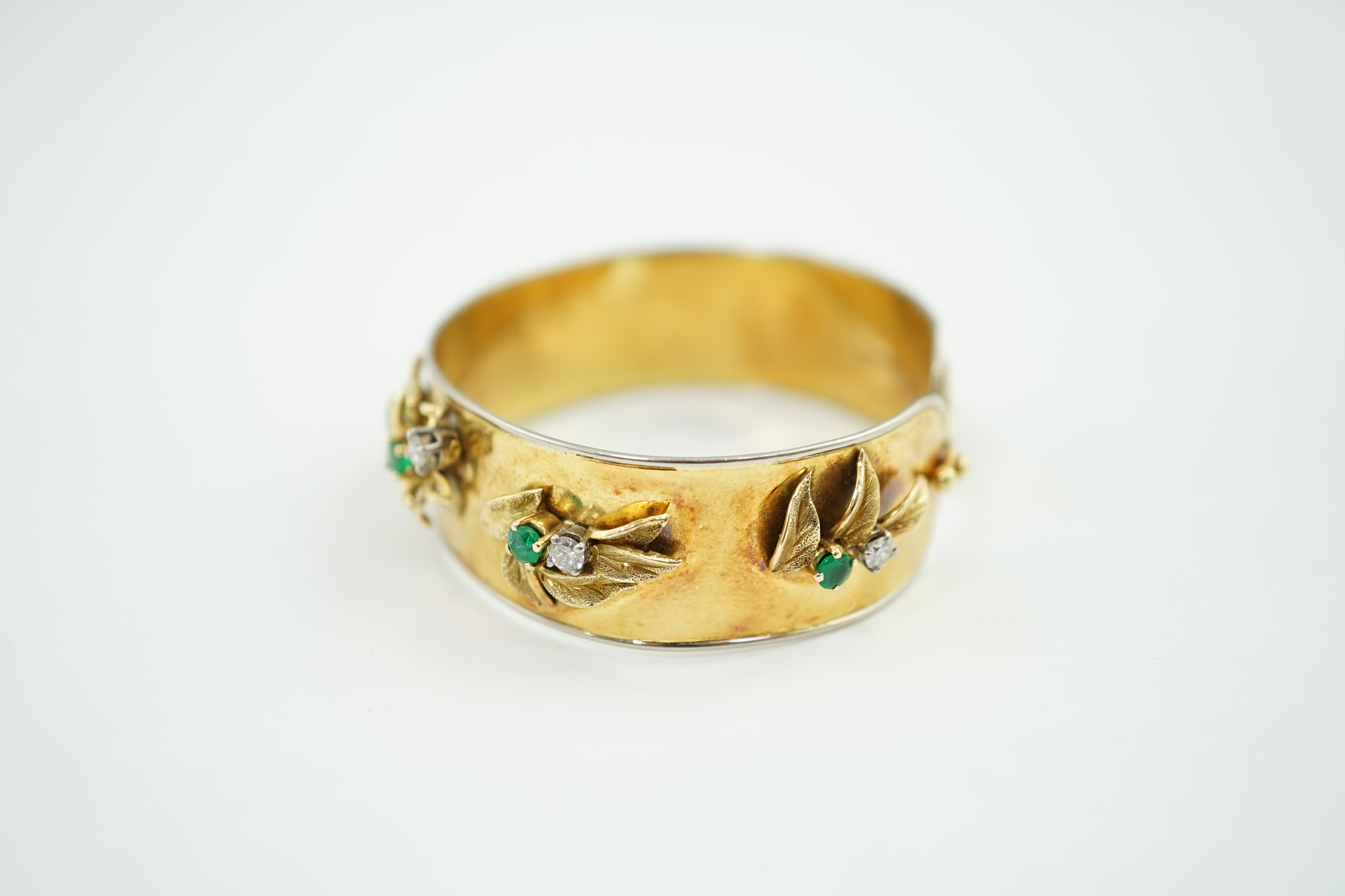 A recent Schwartz 18k gold, emerald and diamond cluster set open bangle with clasp
